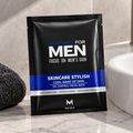 A single black and blue sachet of Men's Skincare Stylish Cool Wake Up Skin oil control facial mask is placed on a marble countertop next to a white sink and a dark gray towel.