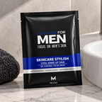 A single black and blue sachet of Men's Skincare Stylish Cool Wake Up Skin oil control facial mask is placed on a marble countertop next to a white sink and a dark gray towel.