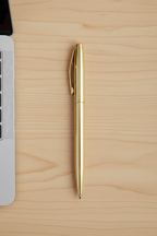 Gold ballpoint pen flat lay on Scandinavian desk with laptop keyboard